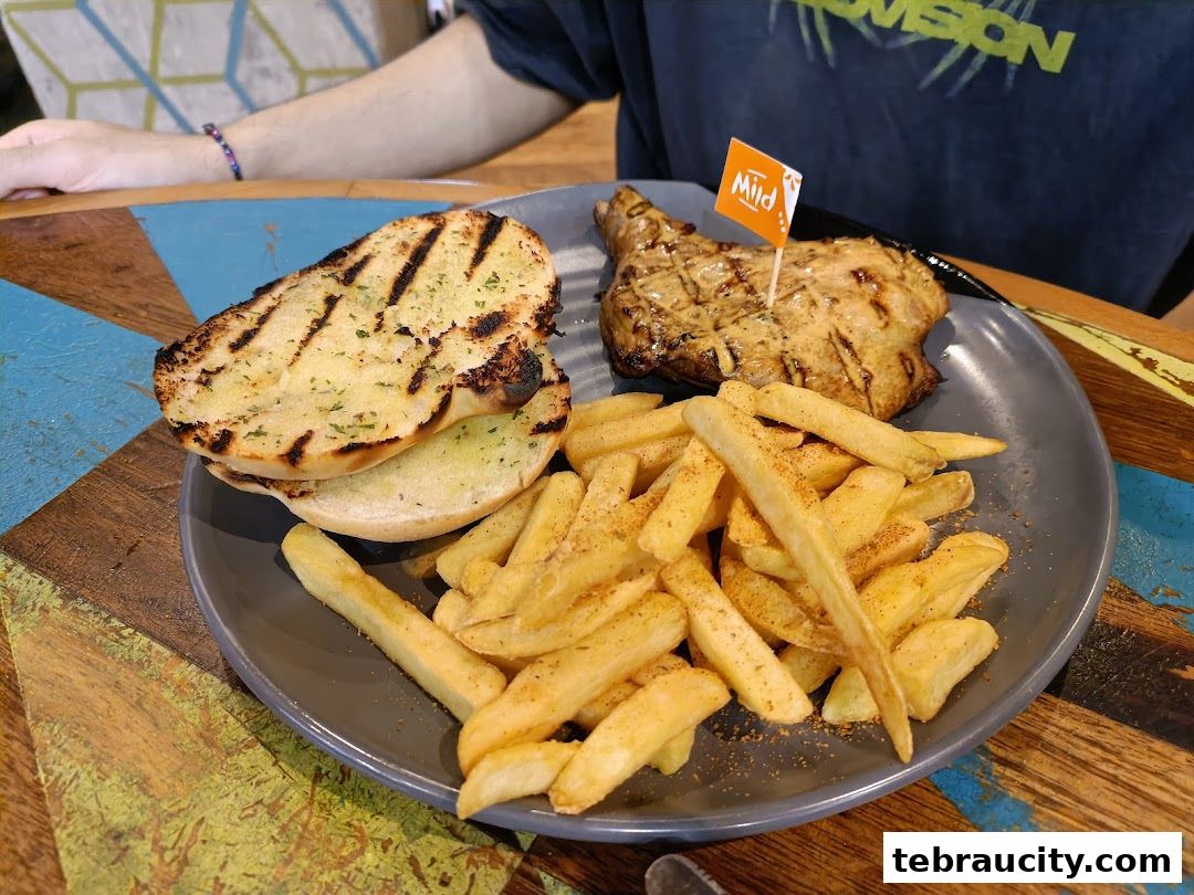 A plate of grilled chicken, fries, and garlic bread with a 'Mild' flag.