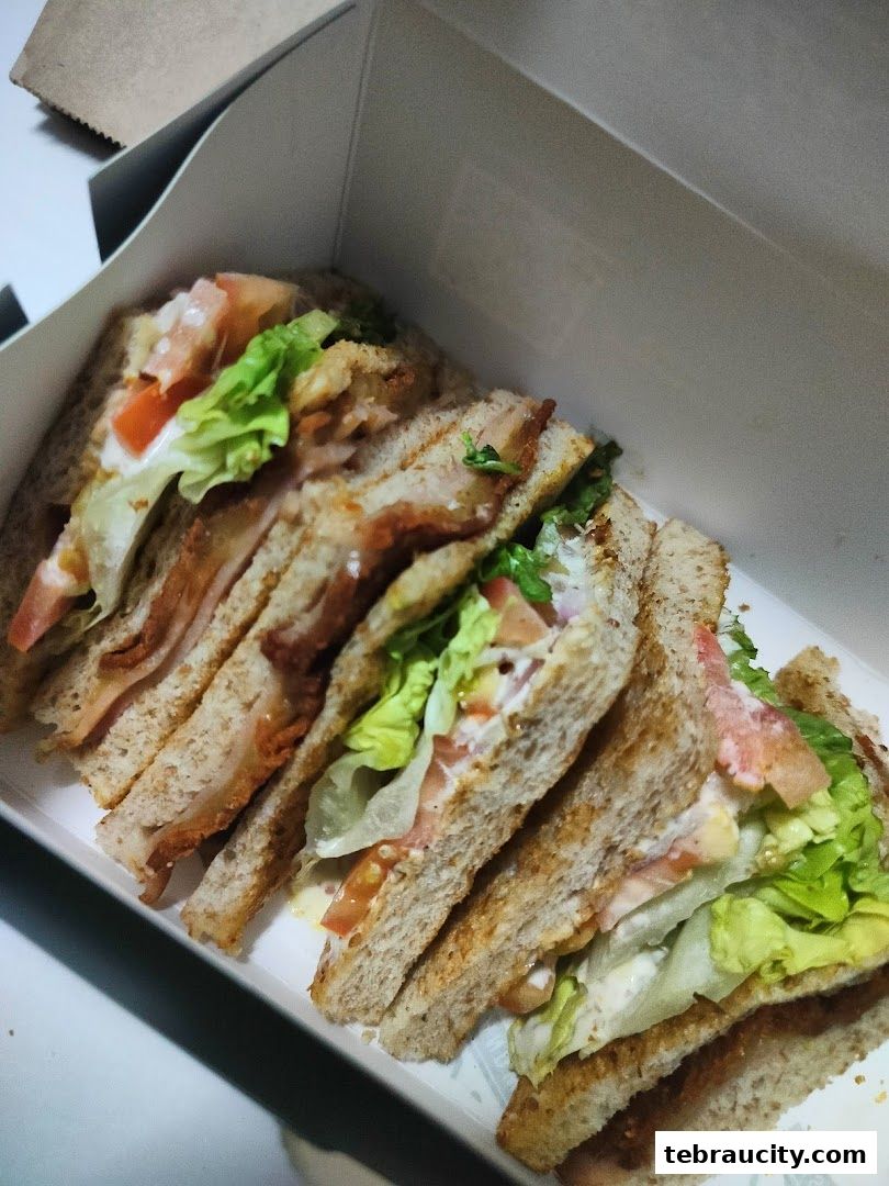 A close-up view of several freshly made sandwiches in a white takeout box.