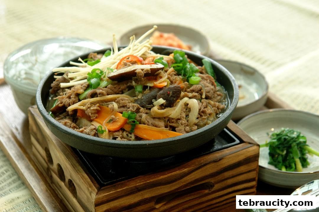 A close-up of a Korean dish with beef, vegetables, and enoki mushrooms.