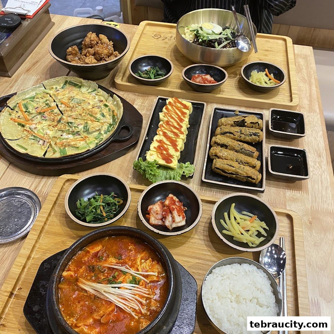 A table filled with various Korean dishes, including kimchi, fried chicken, and stews.