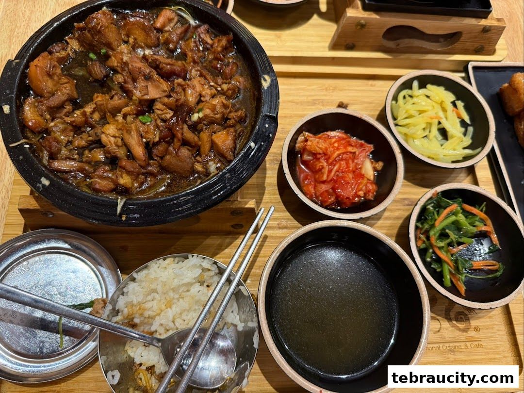A close-up of a Korean meal with braised chicken, rice, kimchi, and side dishes.