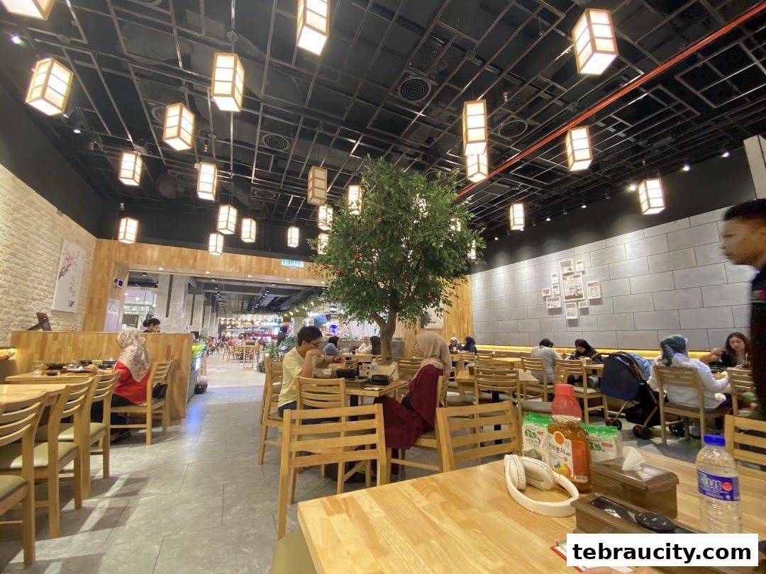 Interior view of a Korean restaurant with wooden tables, chairs, and decorative lighting.