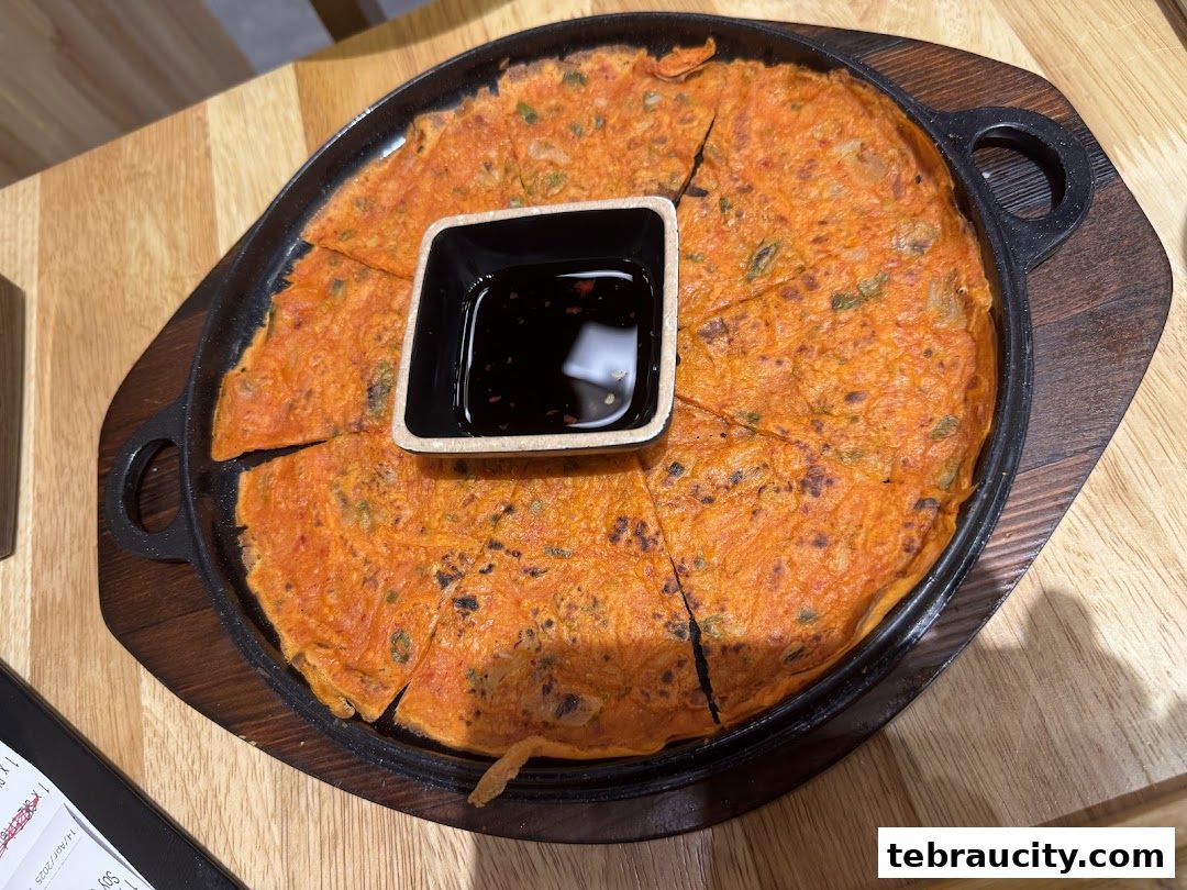 A delicious Korean pancake served in a cast iron pan with dipping sauce.