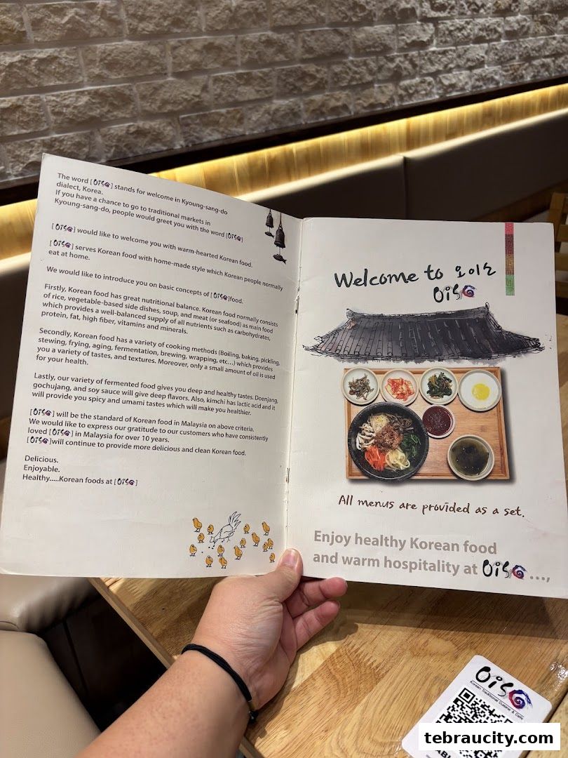 A person holding an open menu for Oiso Korean Restaurant, showcasing Korean food.