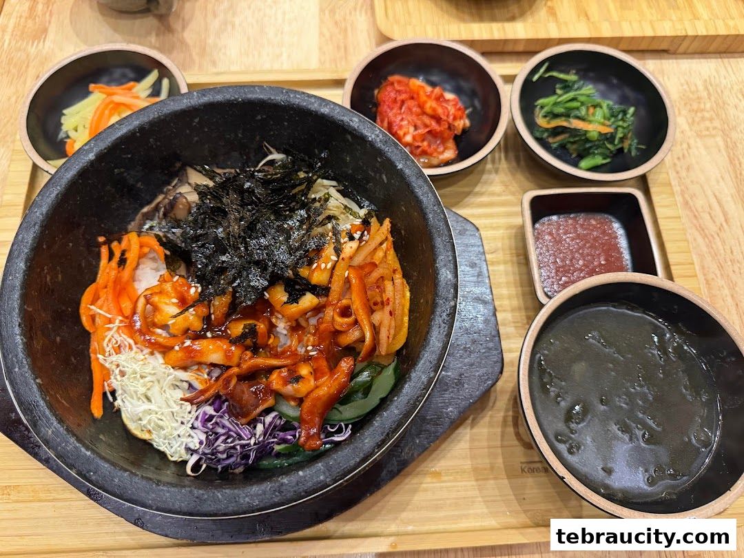 A delicious Korean bibimbap served with various side dishes and a bowl of soup.