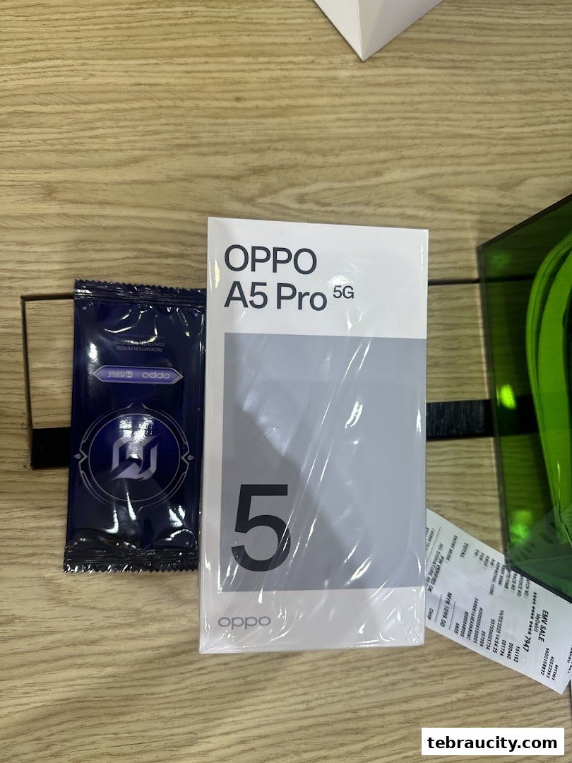 A box of OPPO A5 Pro 5G phone and a small packet on a wooden surface.