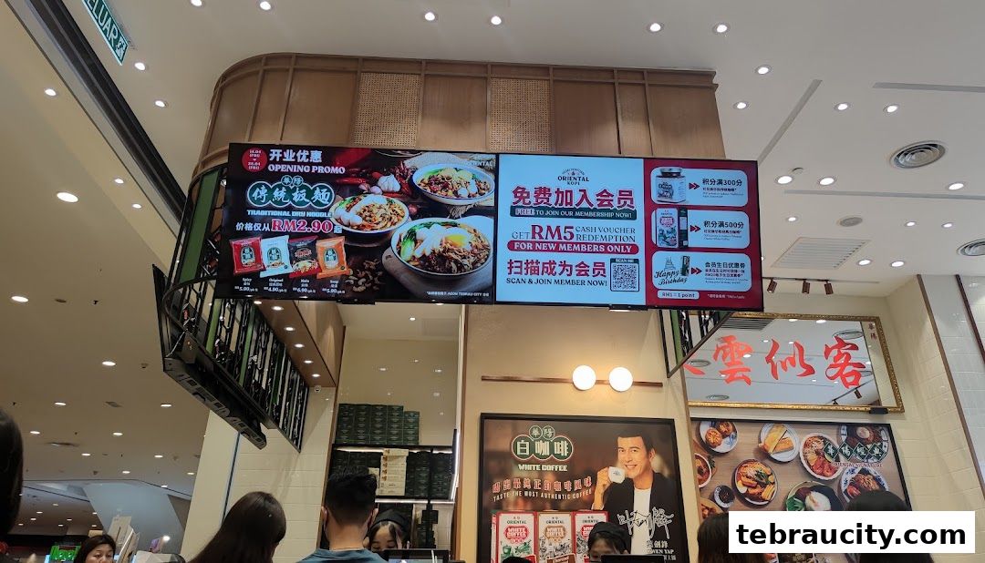 Digital screens display promotions for Oriental Kopi, featuring noodle dishes and membership offers.