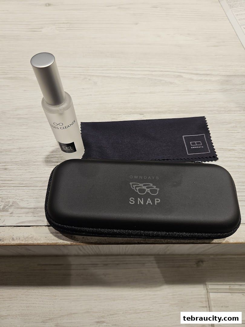 A black glasses case, lens cleaner, and cleaning cloth from OWNDAYS.