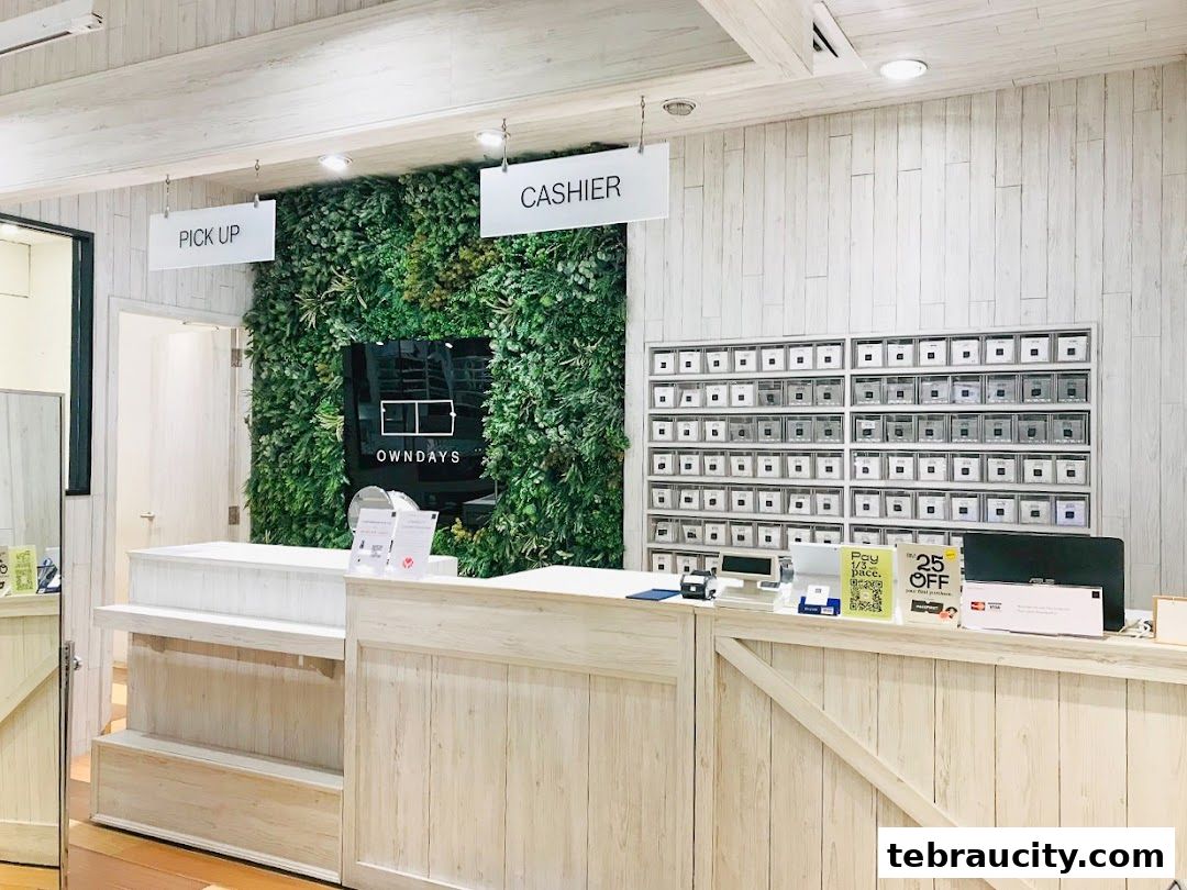 The interior of an OWNDAYS shop with a cashier counter, pick-up sign, and a green wall.
