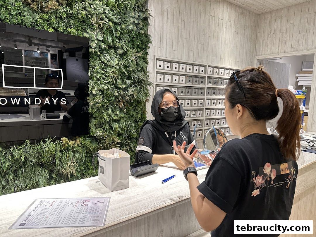 A customer consults with an optician at the OWNDAYS counter, surrounded by eyewear displays.