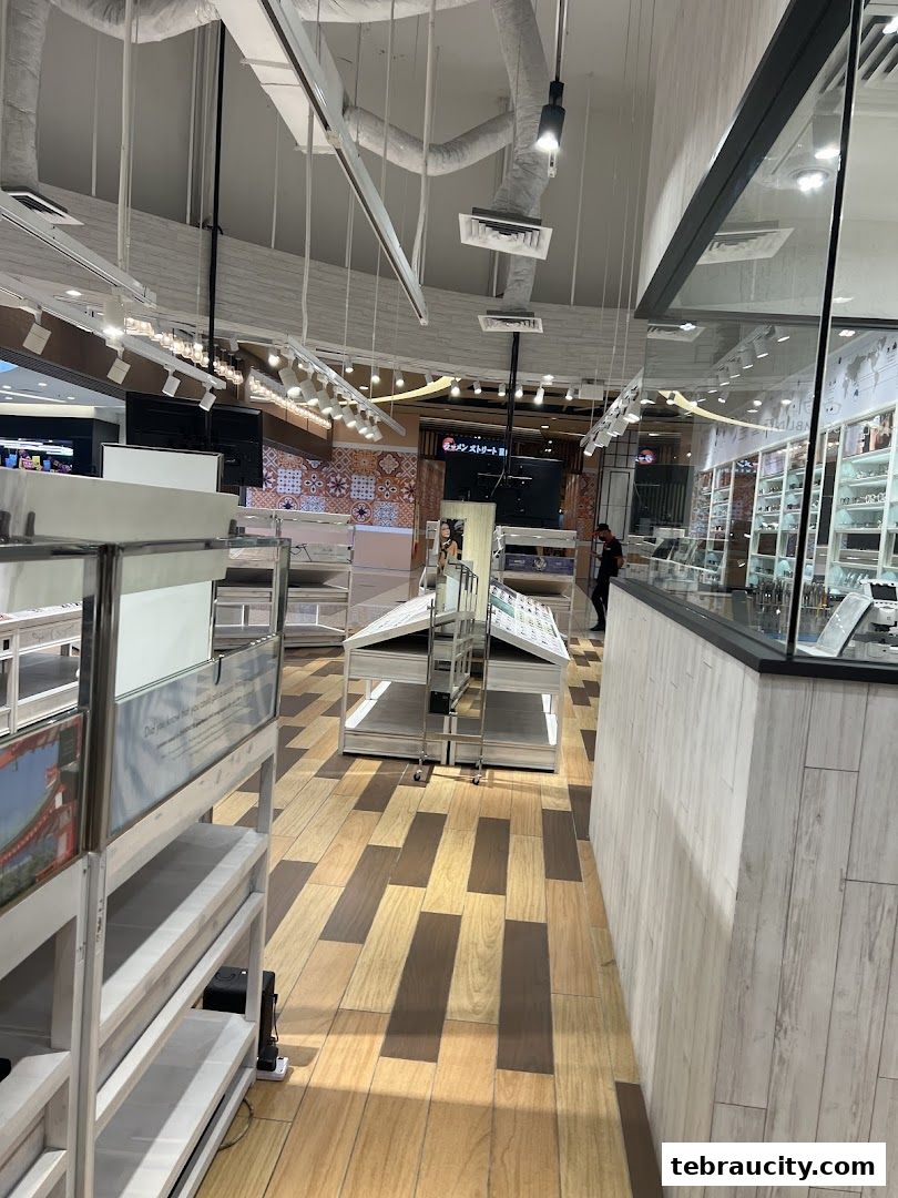 Interior view of an eyewear shop with display shelves and a person walking.