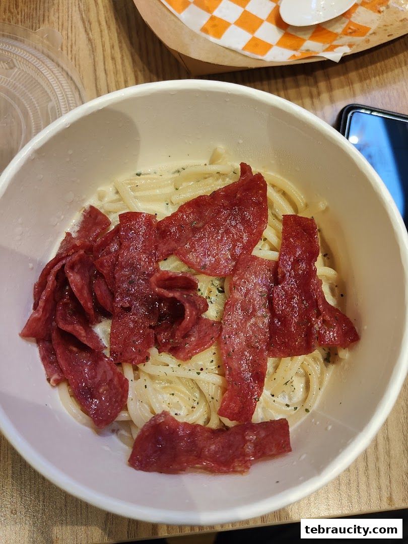 A close-up shot of a creamy pasta dish topped with slices of cured meat.