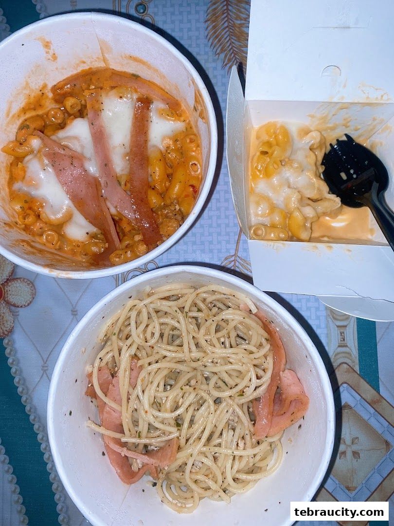 Three takeaway containers filled with pasta dishes, including spaghetti and macaroni and cheese.