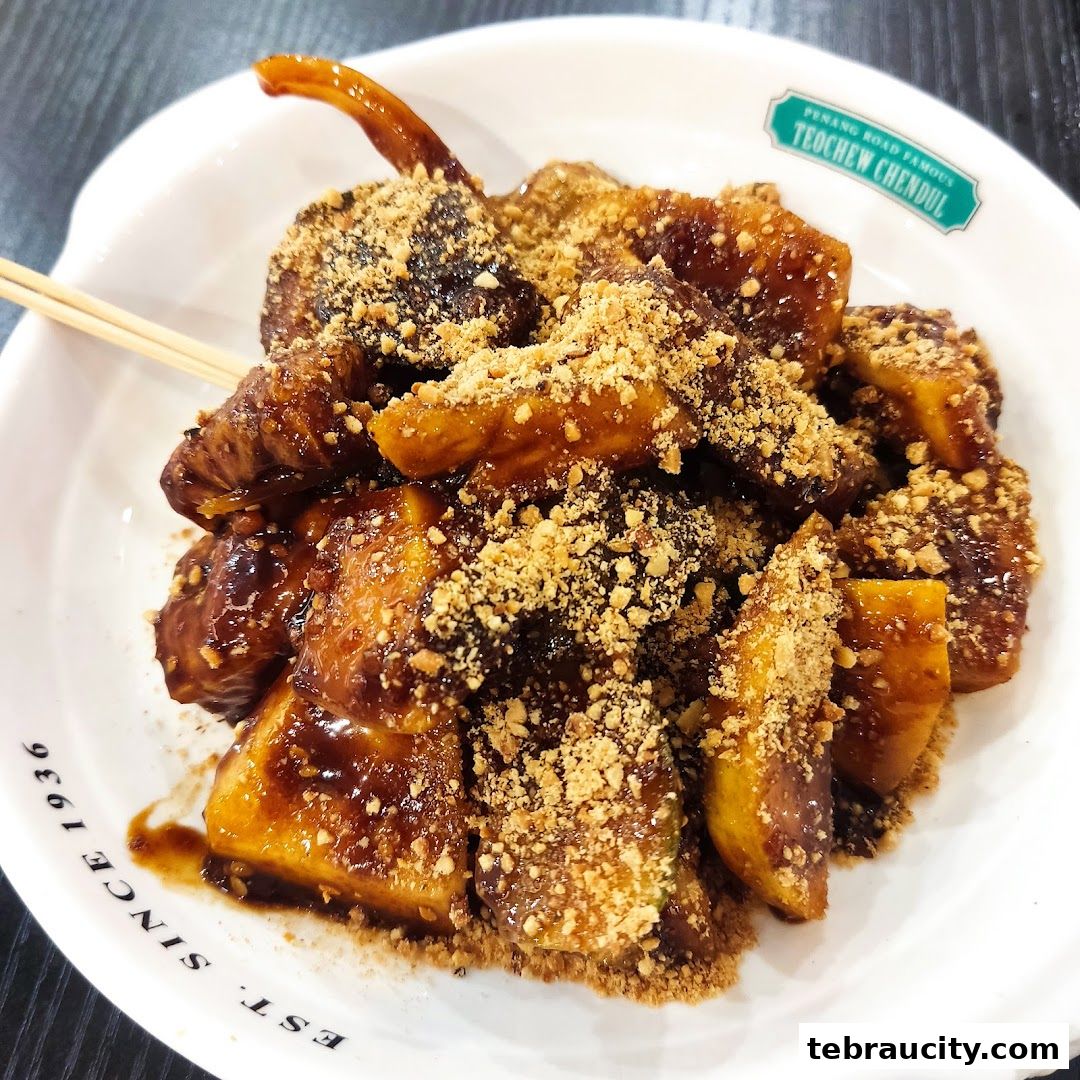 A close-up of a delicious bowl of Penang Road Famous Teochew Chendul dessert with syrup and peanuts.