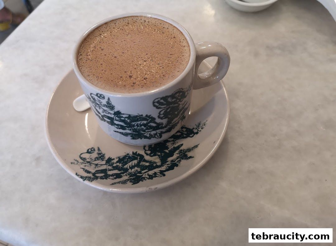 A close-up shot of a frothy cup of coffee served in a vintage-style mug and saucer.