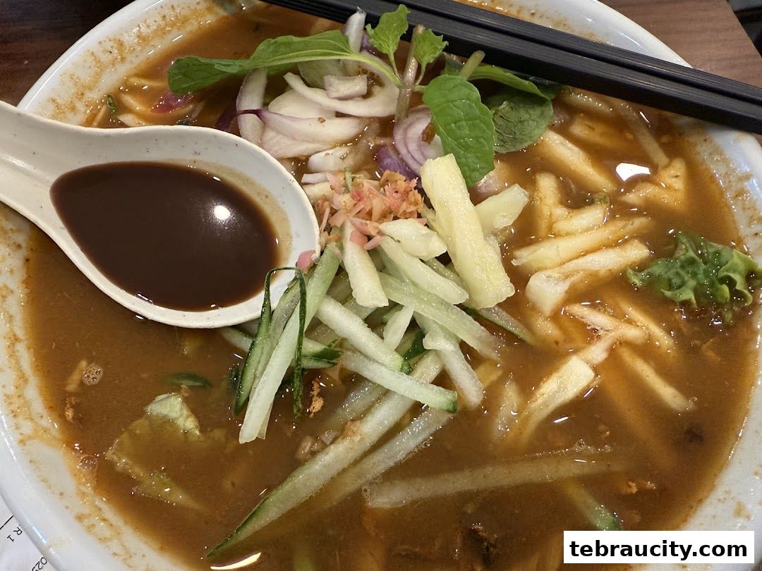 A close-up shot of a delicious bowl of Penang Road Famous Teochew Chendul, featuring noodles, broth, and fresh toppings.