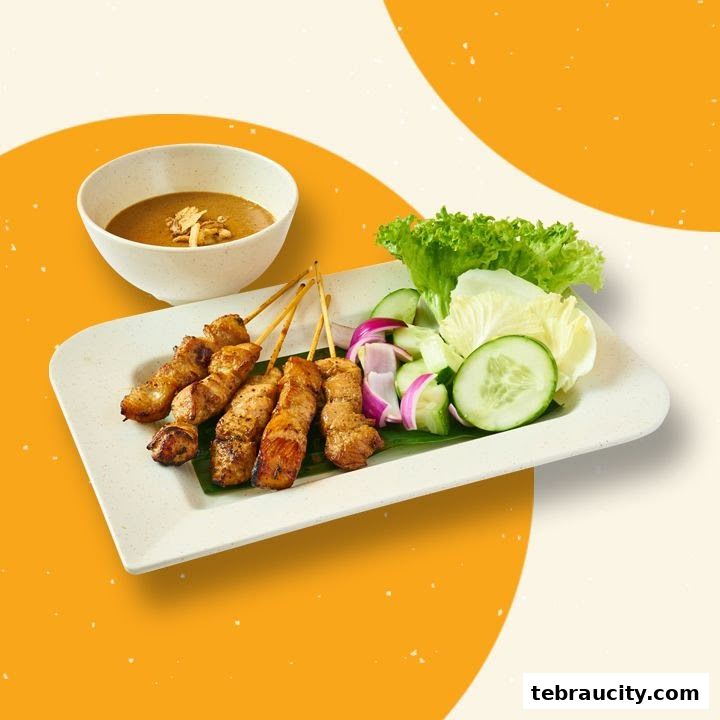 A plate of grilled chicken satay with peanut sauce and fresh cucumber and lettuce.