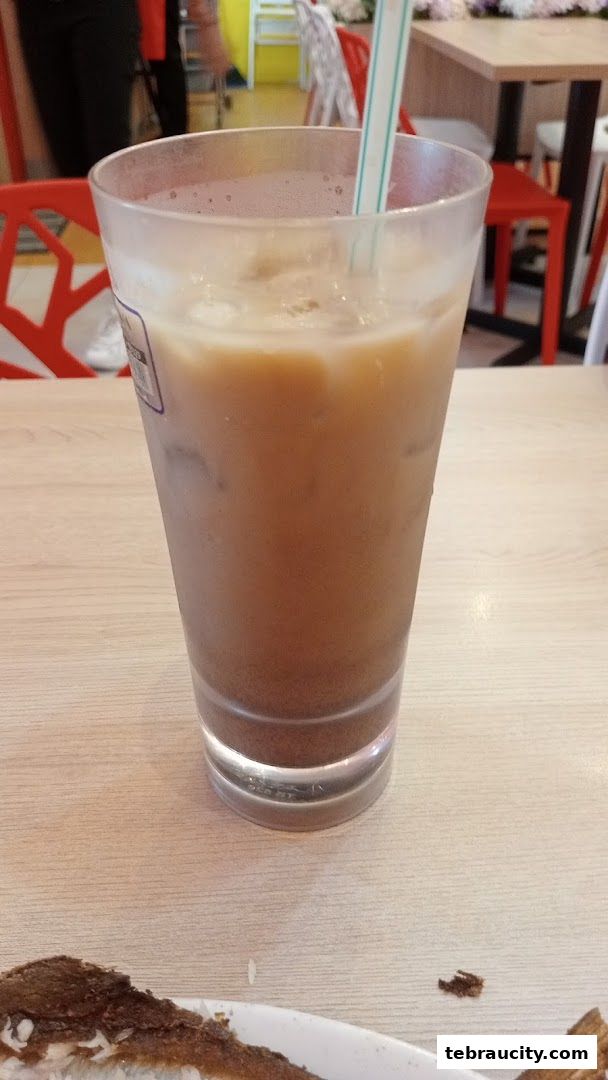 A close-up of a refreshing iced coffee drink with a straw in a clear glass.