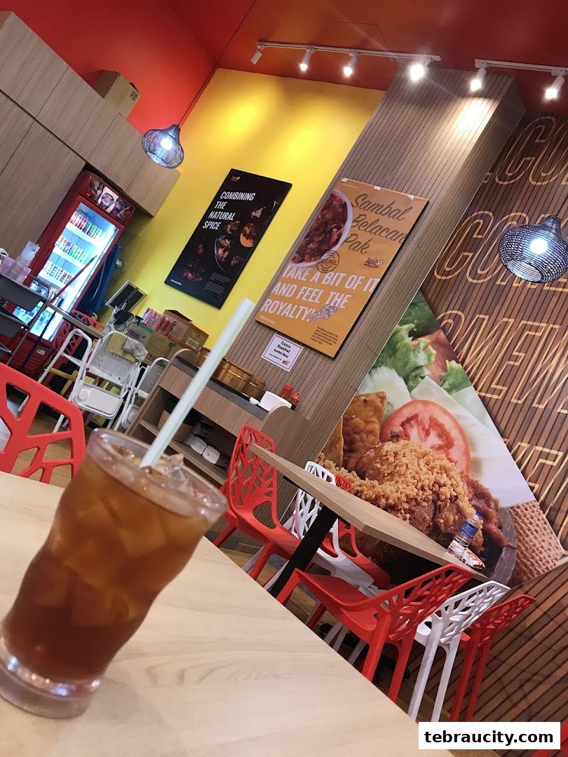 Interior of a restaurant with a drink in the foreground and promotional posters on the wall.