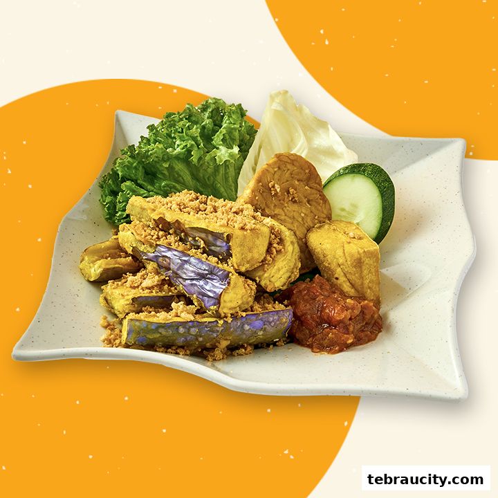 A plate of fried eggplant, tofu, and tempeh with sambal and fresh vegetables.