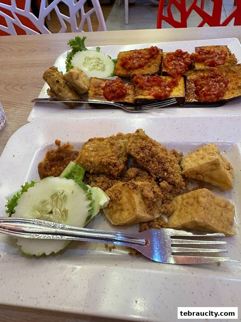 Two plates of Indonesian food, featuring fried tofu and eggplant with chili sauce.