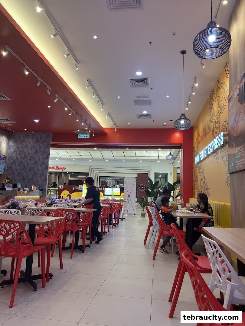 Interior view of Penyet Express restaurant with red chairs and tables.
