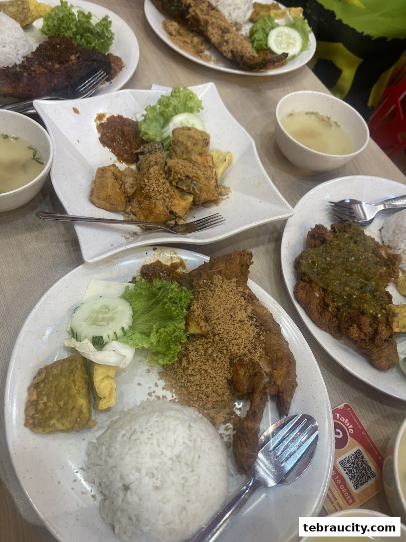 Plates of Indonesian fried chicken and fish with rice and soup.