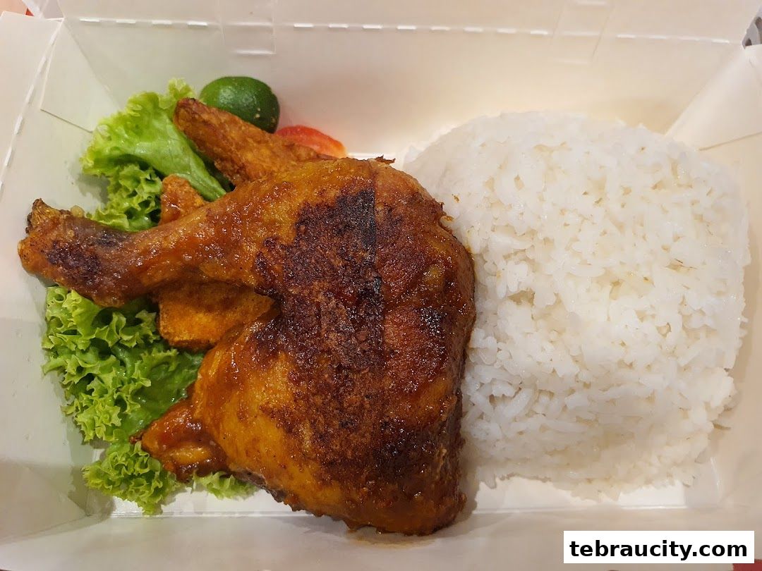 A close-up of a PenyetPenyet meal featuring grilled chicken, rice, and salad.