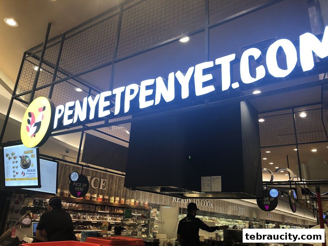 The PenyetPenyet shop front with a large illuminated sign and a display of food items.