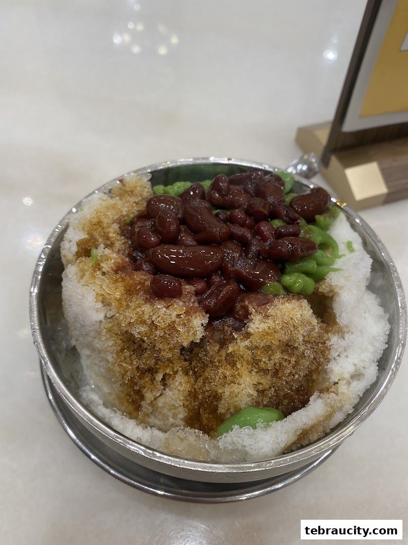 A close-up of a refreshing bowl of Cendol with red beans and shaved ice.