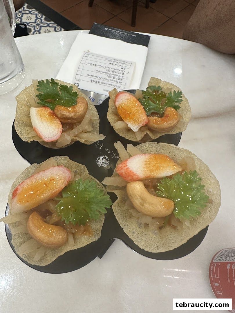 Four crispy appetizers topped with crab sticks, cashews, and herbs on a table.