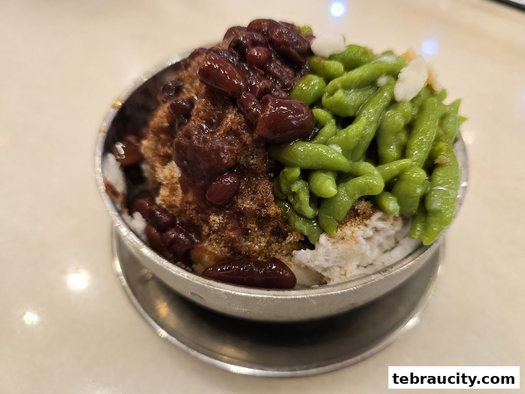 A close-up of a refreshing bowl of Cendol with red beans and shaved ice.