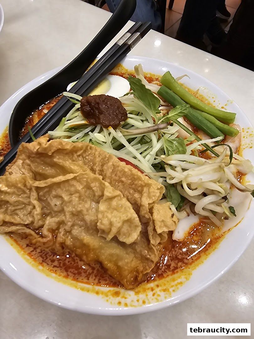 A close-up shot of a delicious bowl of Laksa with various toppings and chopsticks.