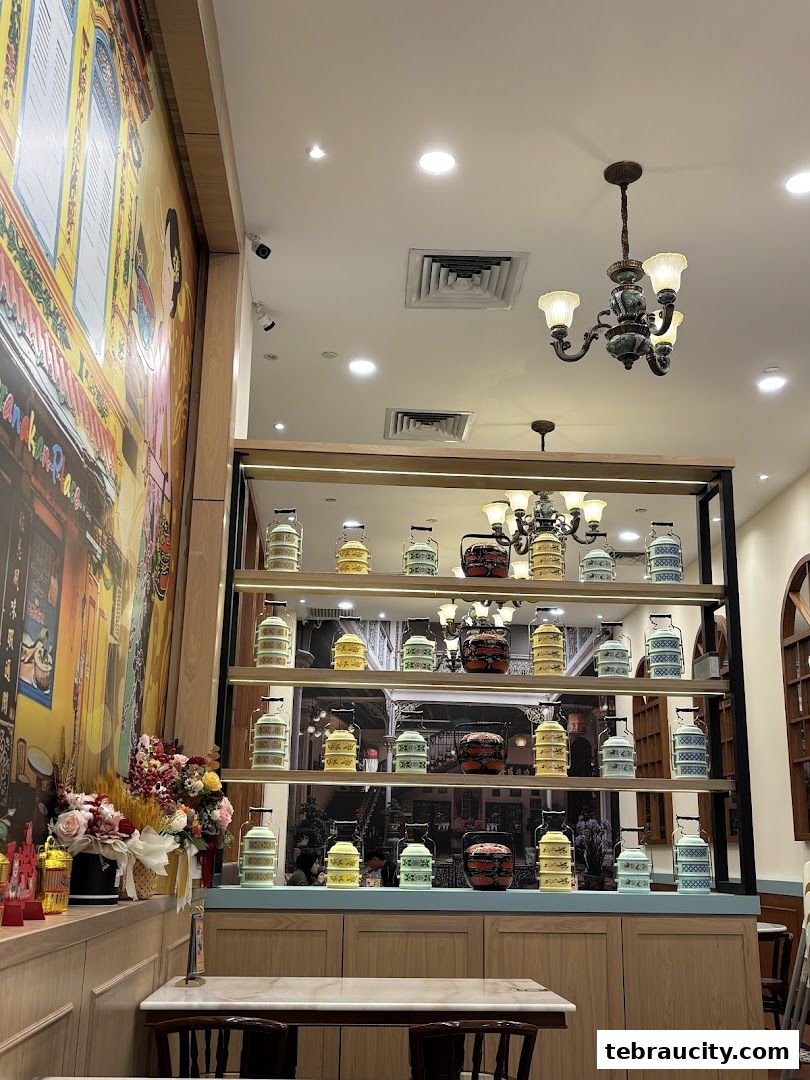 Interior of a Peranakan restaurant with colorful tiffin carriers displayed on shelves.