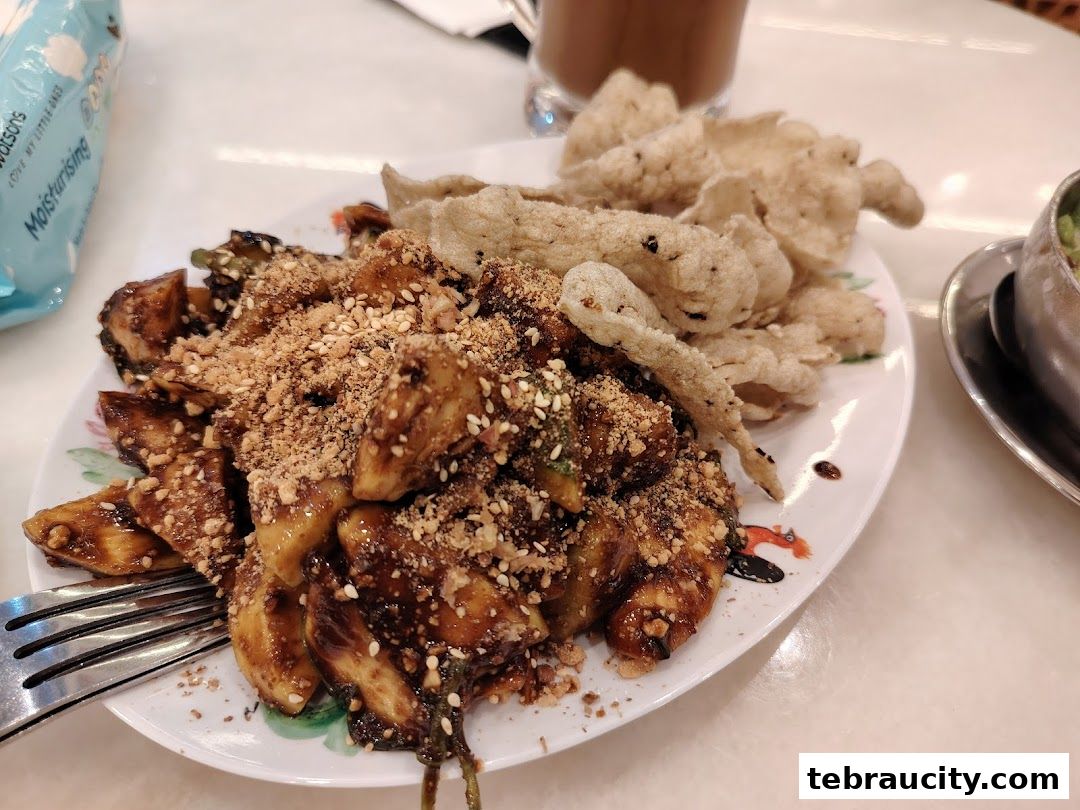 A plate of rojak with crushed peanuts and crackers, served with a drink.