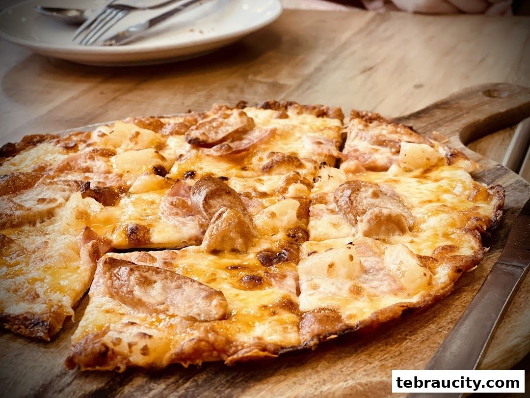 A delicious pizza with ham and pineapple toppings served on a wooden board.