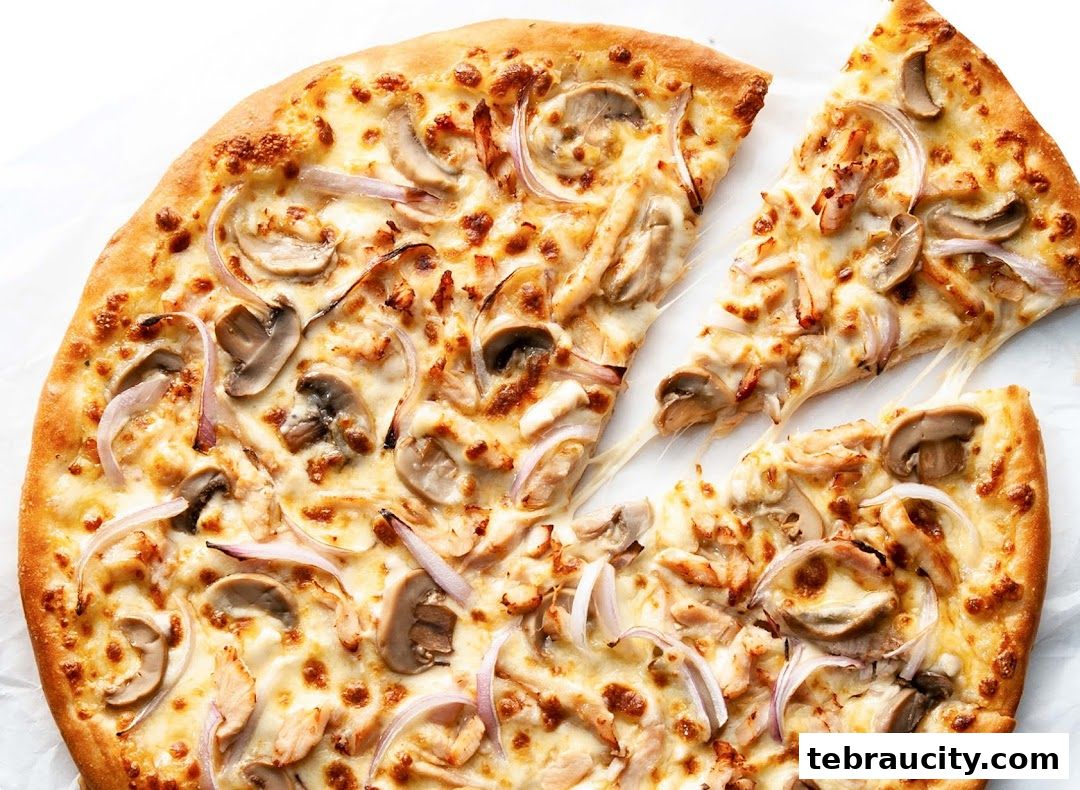 A delicious Pizza Hut pizza with chicken, mushrooms, and onions, with a slice being pulled away.