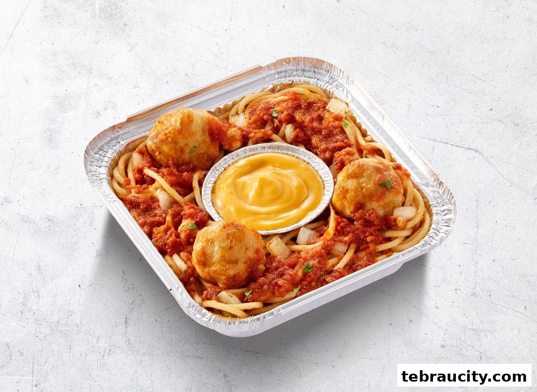 A delicious serving of spaghetti with meatballs and a side of cheese dip in a foil container.