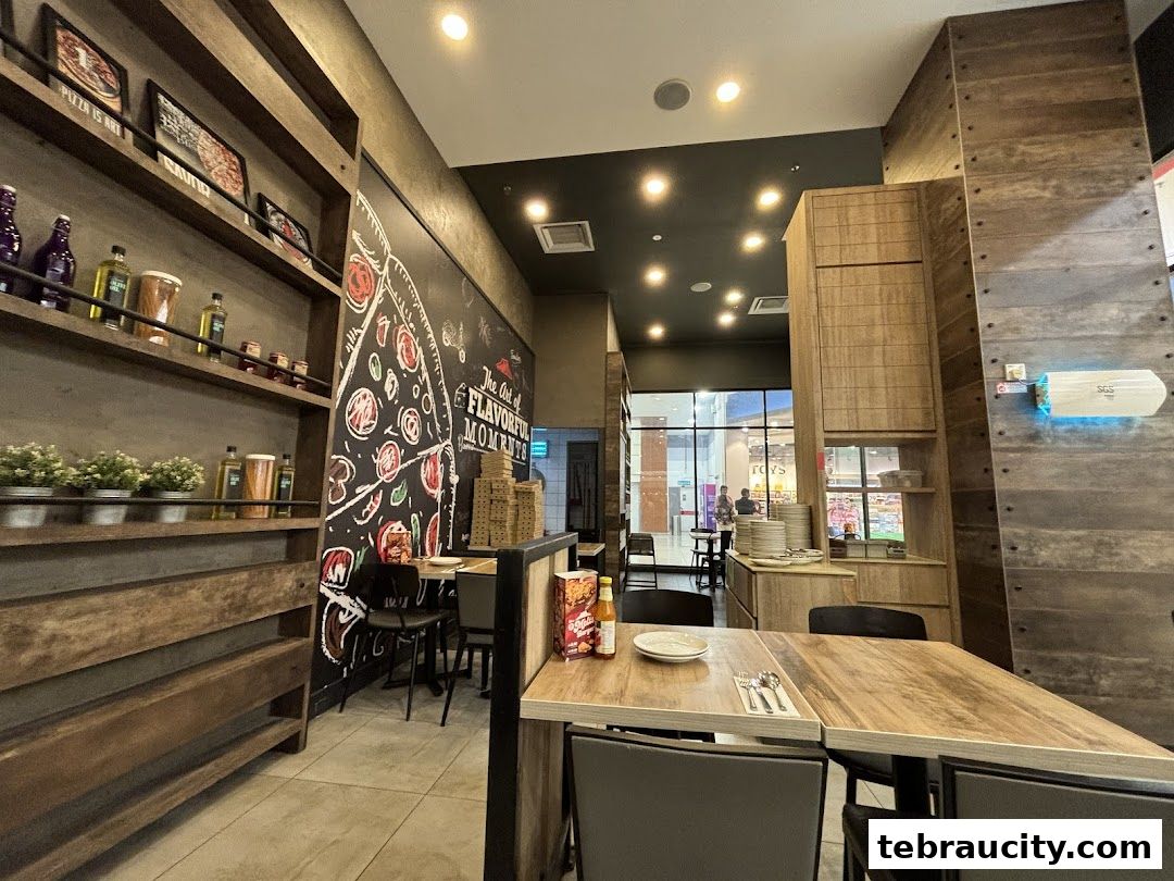 Interior view of a Pizza Hut restaurant with tables, shelves, and a pizza mural.