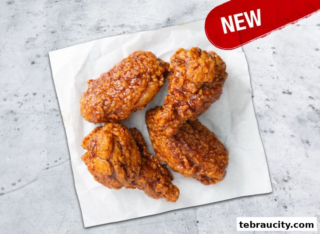 Four pieces of crispy, glazed chicken wings are presented on white paper.