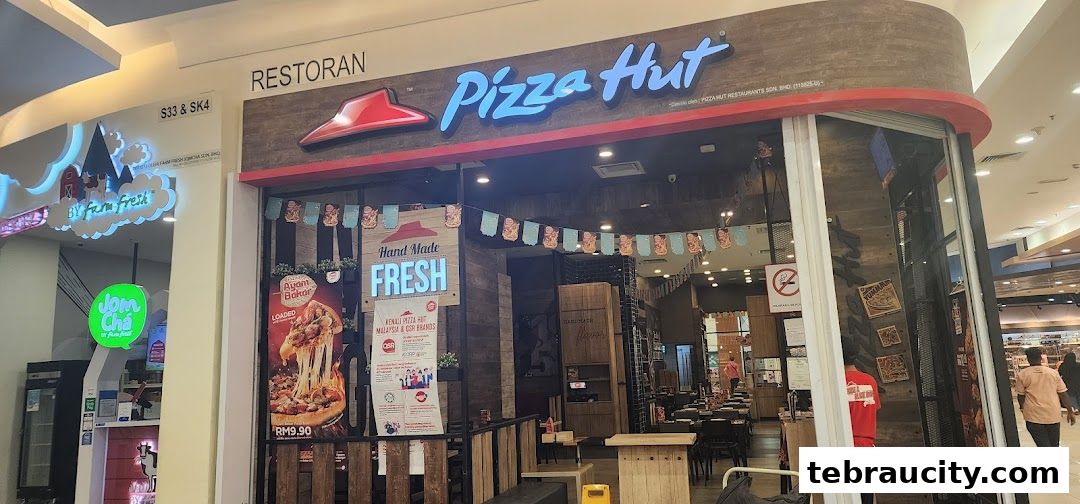 The exterior of a Pizza Hut restaurant with its iconic logo and a display of a loaded pizza.