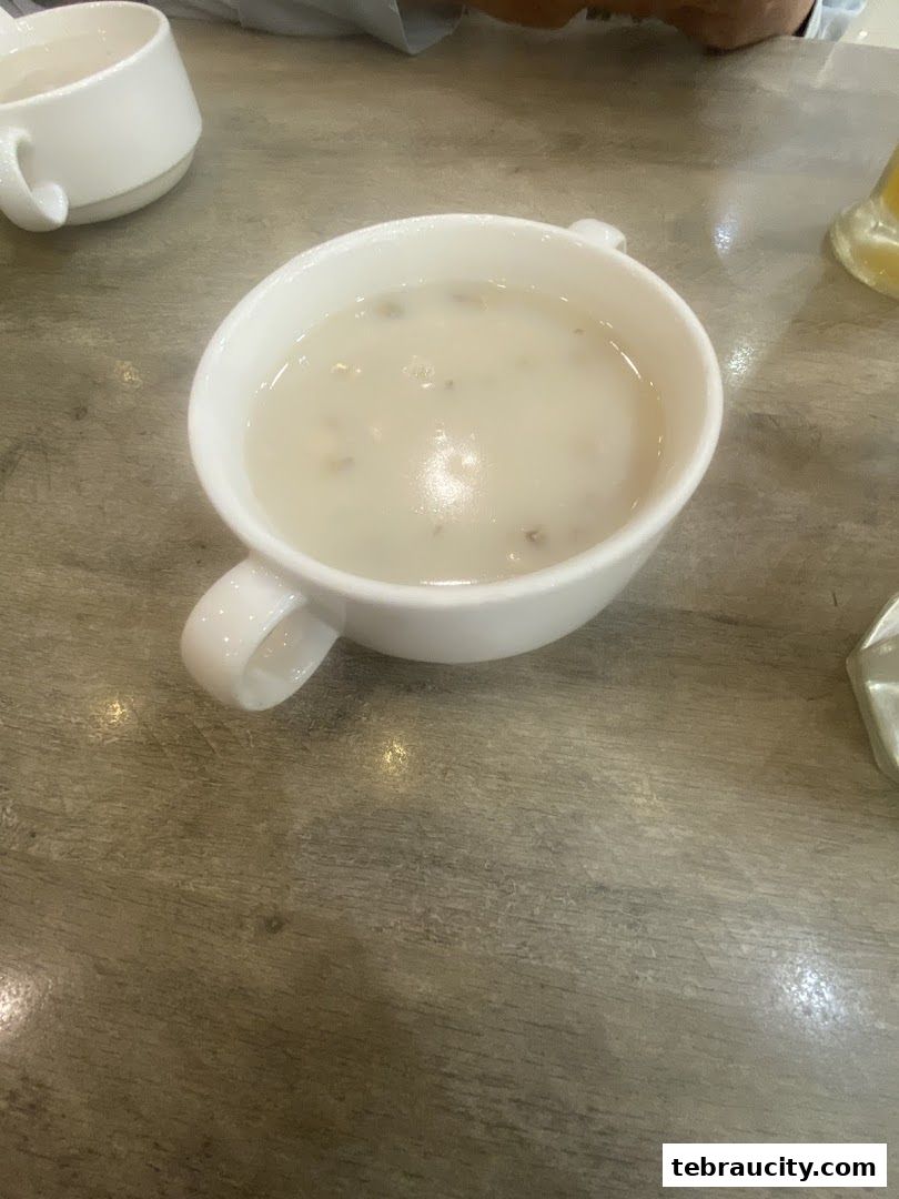 A close-up shot of a bowl of creamy mushroom soup on a wooden table.