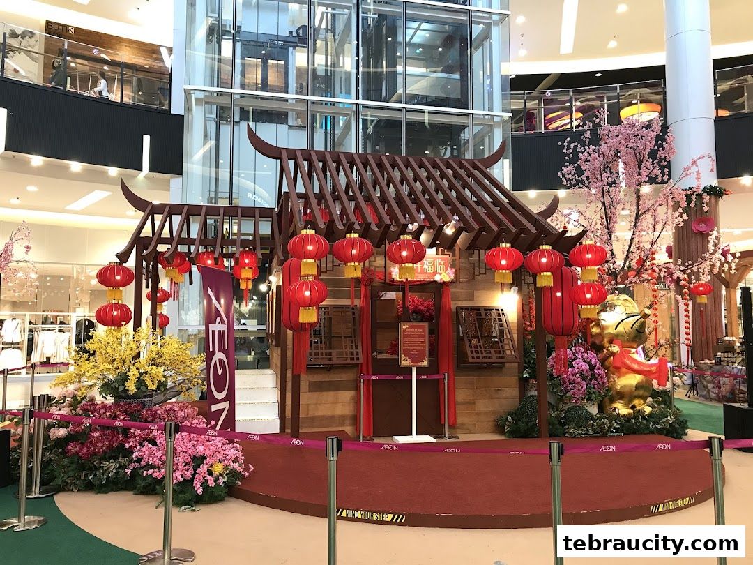 A festive Chinese New Year display with a traditional house, lanterns, flowers, and a golden statue.