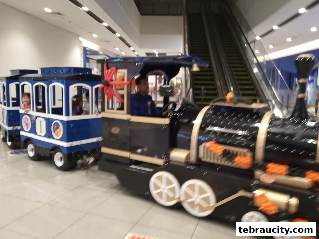 A children's train ride with kids and a driver inside a shopping mall.