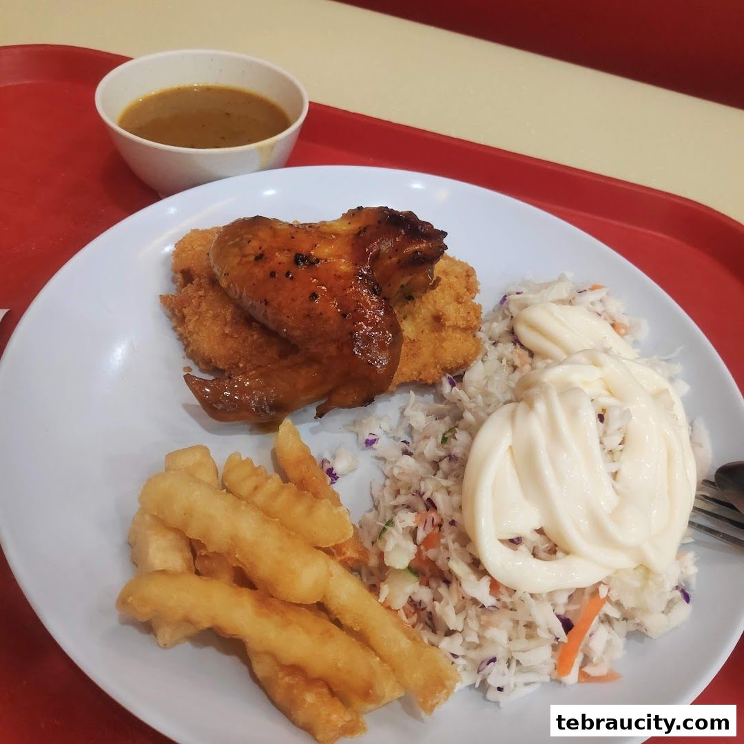 A plate of fried chicken, fries, coleslaw, and gravy on a red tray.