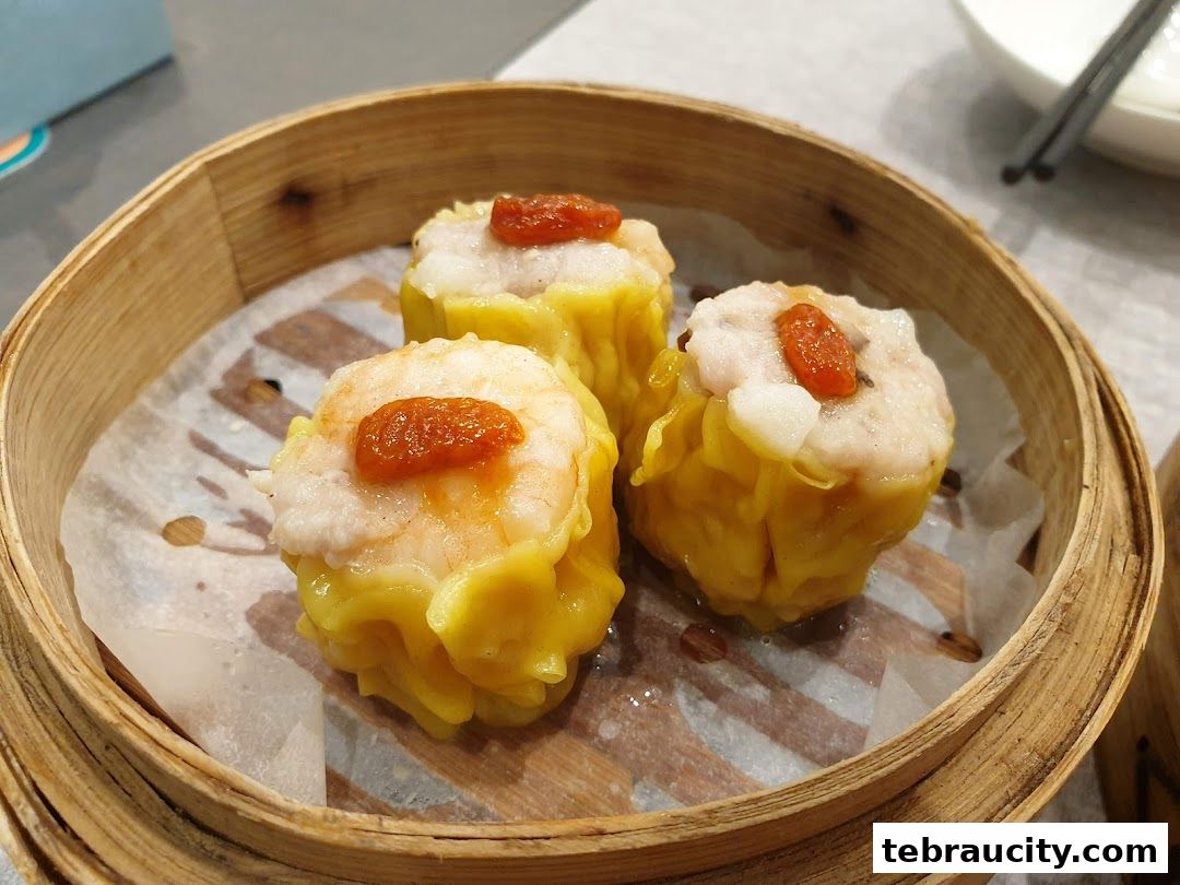 Three delicious shrimp siu mai dumplings served in a bamboo steamer basket.