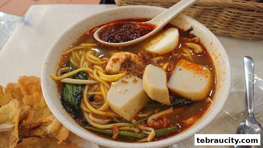 A close-up shot of a delicious bowl of noodle soup with shrimp, fish cakes, and a hard-boiled egg.
