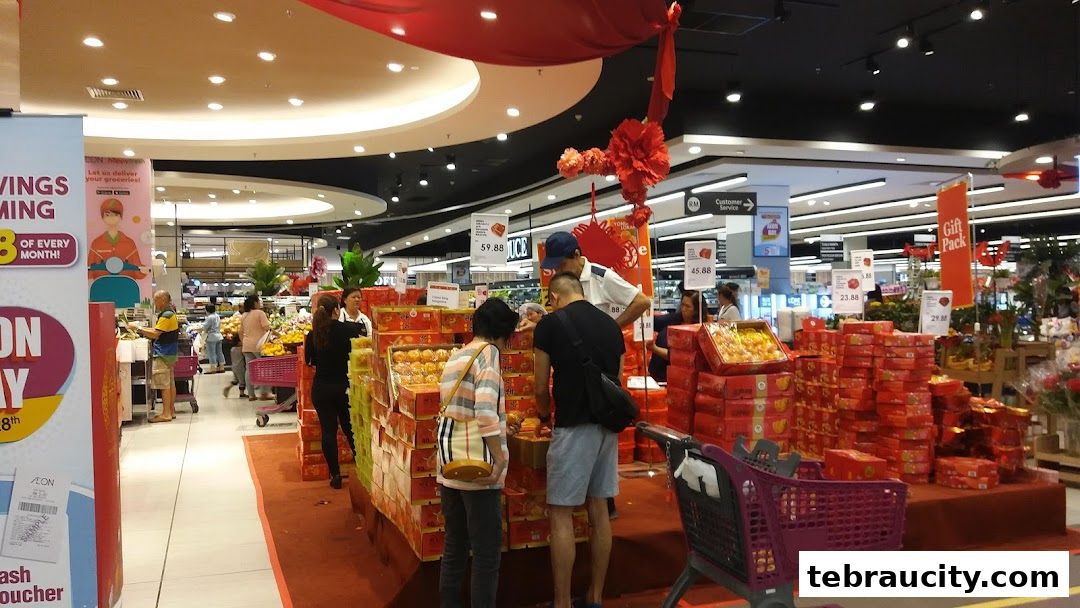A busy supermarket aisle with customers browsing festive gift boxes and produce.
