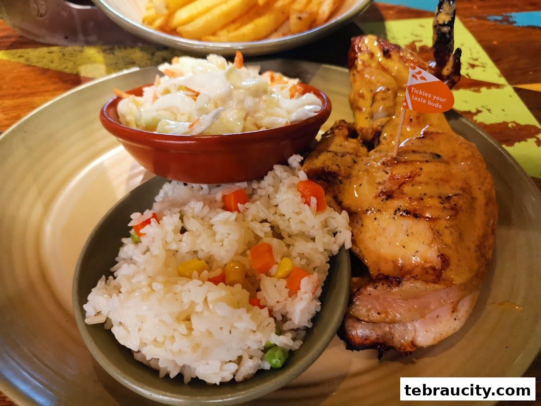 A plate of grilled chicken with rice and coleslaw, garnished with a small flag.