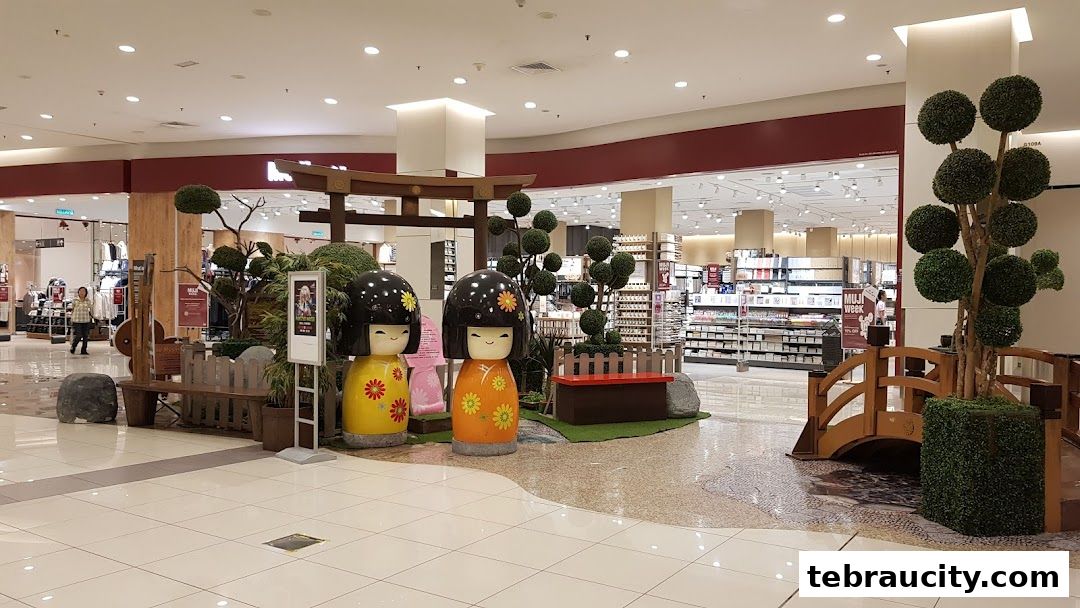A Japanese-themed display with large Kokeshi dolls and decorative trees in a shopping mall.